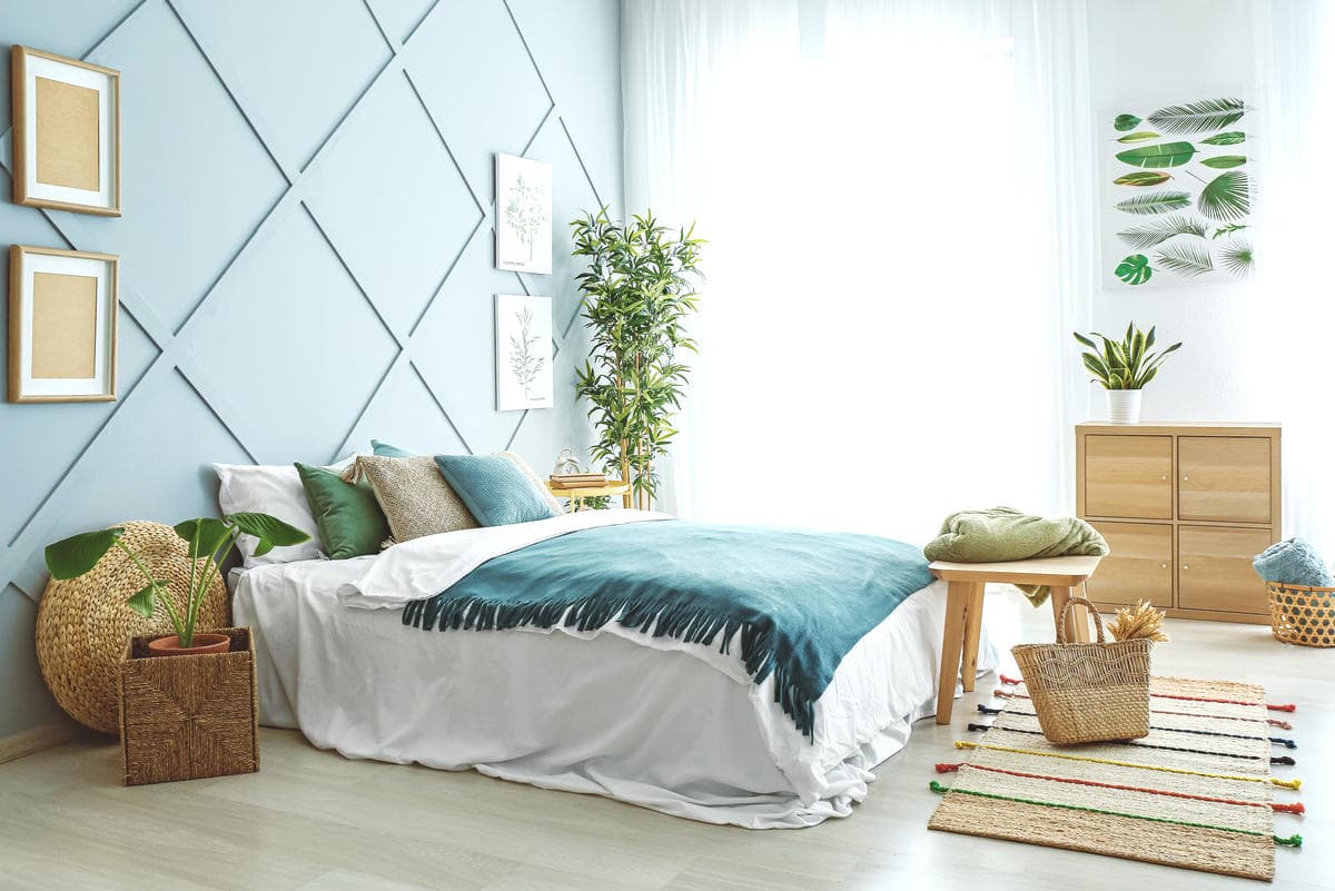 Bright, tidy bedroom with made bed, plants, and woven baskets, calm home cleaning and organizing inspiration.