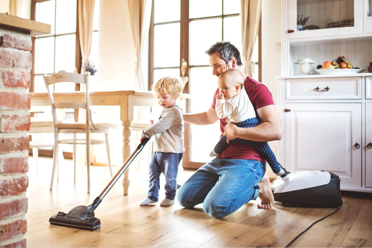 Dad and child vacuuming the floor, simple weekly cleaning plan for a busy home.